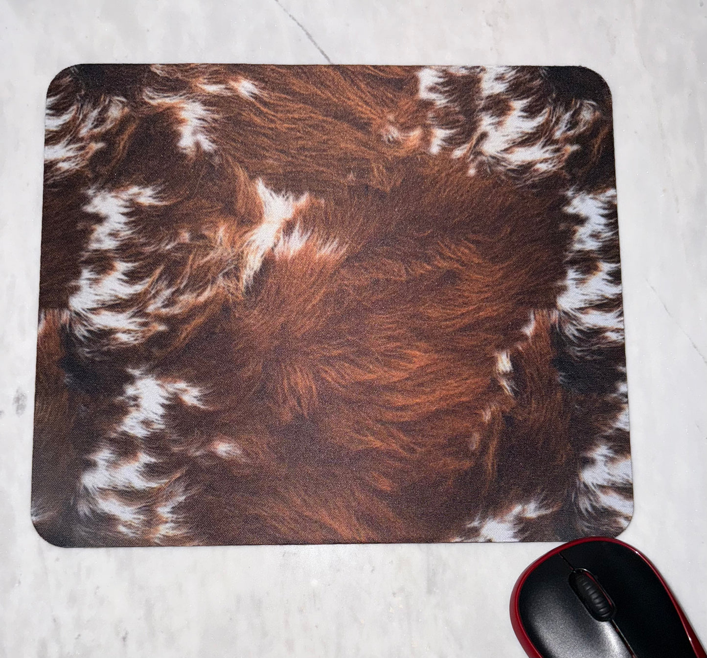 Mouse pad with brown and white cowhide pattern .