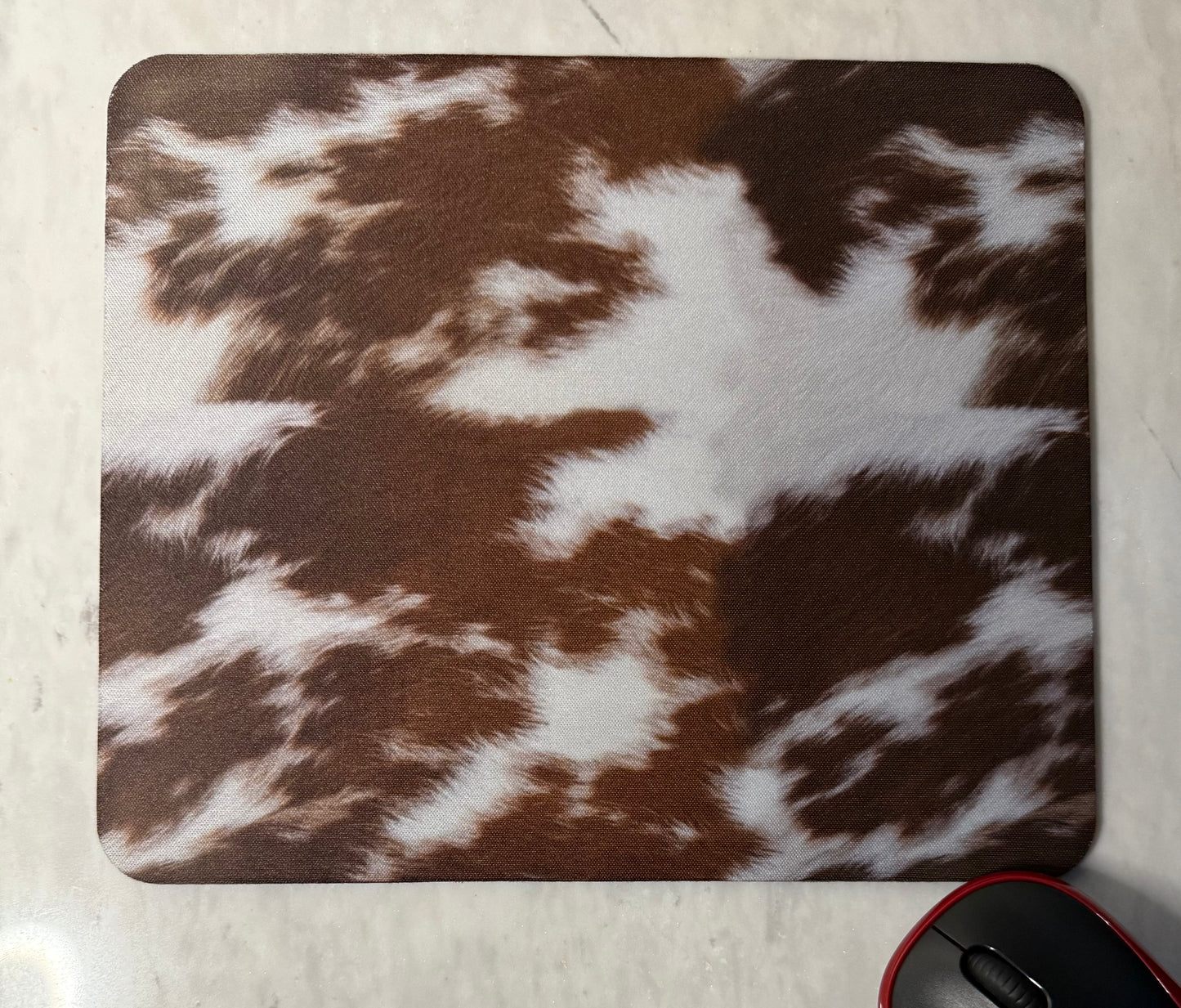 Mouse pad with brown and white cow print pattern .